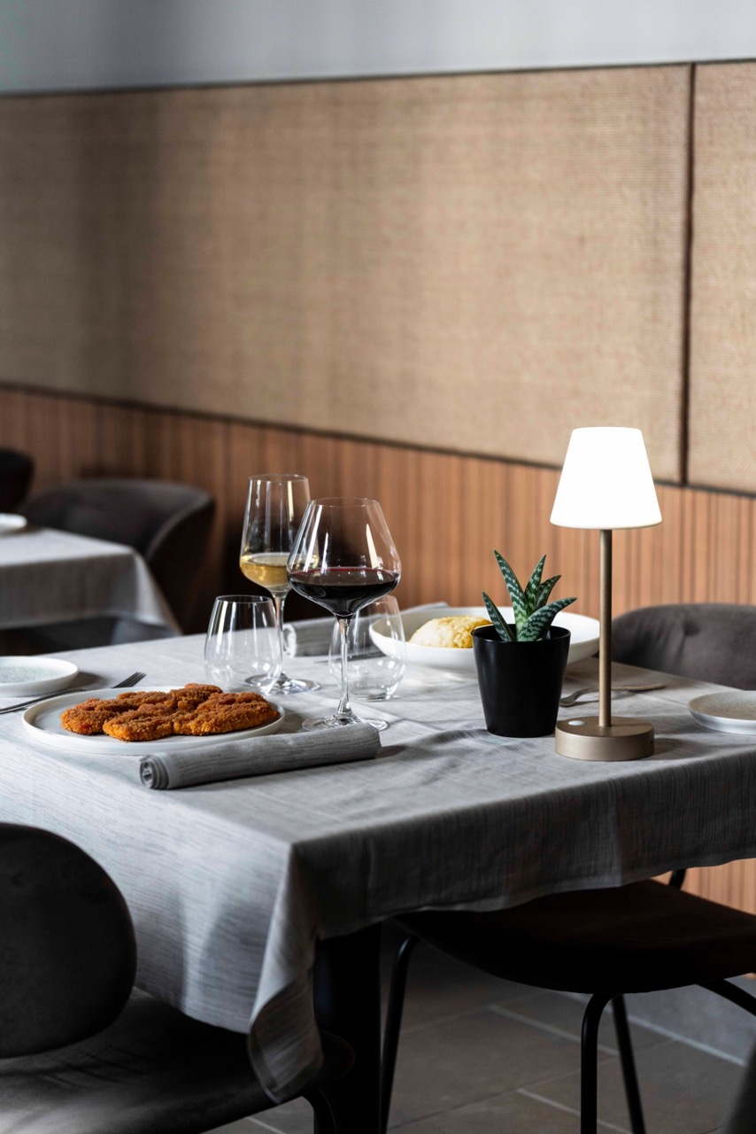 tavolo ristorante con piatto di cotoletta alla milanese e risotto al salto